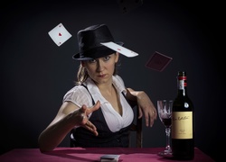Kobieta siedząca przy stole z butelką wina rzuca karty