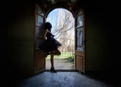 Kobieta stojąca przy otwartych drzwiach z widokiem na ogród