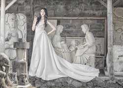 Kobieta w białej sukni obok rzeźb