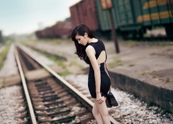 Kobieta w czarnej sukience na torach kolejowych