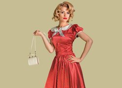 Kobieta w czerwonej sukience w kropki z torebką