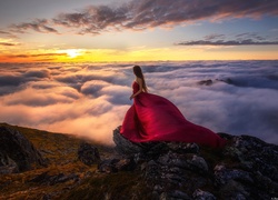 Kobieta w czerwonej sukni wśród mgły o zachodzie słońca