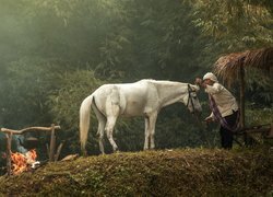 Kobieta z białym koniem przy ognisku