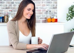 Kobieta z kubkiem kawy przy laptopie