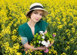 Kobieta z kwiatami na rzepakowym polu