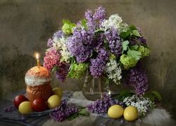 Kompozycja z pisankami na talerzyku, babeczką i kwiatami bzu w wazonie