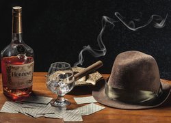 Koniak w butelce obok cygara na popielniczce i kapelusza