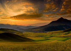 Krajobraz wzgórz i pól w blasku zachodzącego słońca