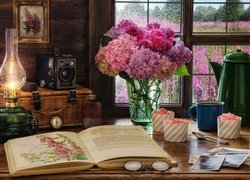 Książka na stole obok dzbanka i bukietu hortensji przy oknie