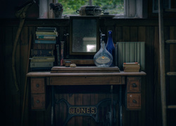 Książki i butelki na maszynie do szycia w starym wnętrzu