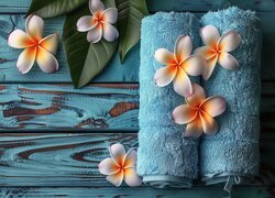 Kwiaty plumerii i ręczniki na deskach