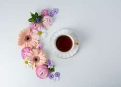 Kwiaty ułożone obok filiżanki z herbatą