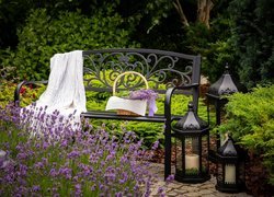 Lampiony obok metalowej ławeczki w ogrodzie