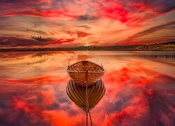 Łódka na jeziorze pod zaróżowionym niebem