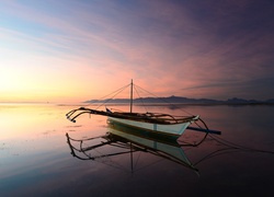 Łódka na jeziorze w świetle wschodzącego słońca