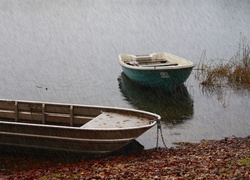 Łódki przycumowane do brzegu stawu w deszczu