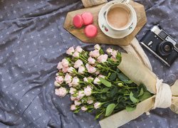 Makaroniki i filiżanka kawy obok bukietu róż