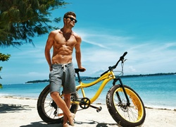 Mężczyzna obok roweru na plaży