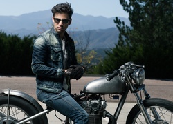 Mężczyzna w okularach i dżinsowej kurtce na motocyklu
