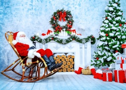 Mikołaj relaksuje się w fotelu bujanym przy kominku i choince