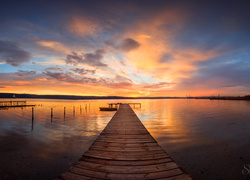 Pomost z łódką na jeziorze o zachodzie słońca