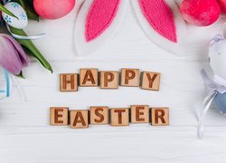 Napis Happy Easter pośród pisanek i tulipanów