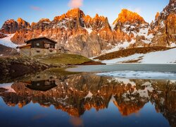Odbicie rozświetlonego szczytu Cimon della Pala i schroniska Baita Segantini i w jeziorze