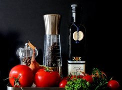 Oliwa i pomidory obok młynków z pieprzem