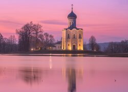 Oświetlona cerkiew i bezlistne drzewa nad rzeką