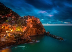 Oświetlona miejscowość Manarola na skałach nad morzem we Włoszech nocą