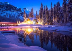 Oświetlony dom nad jeziorem Emerald Lake zimową porą
