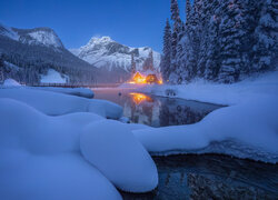 Oświetlony dom nad jeziorem w scenerii zimowej