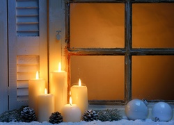 Parapet okna świątecznie ozdobiony świecami i bombkami