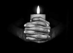 Płonąca świeca w dłoniach