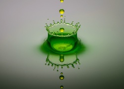 Plusk zielonej kropli wpadającej do wody