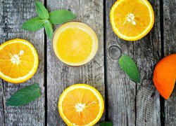 Pokrojone pomarańcze i szkalnka soku na deskach