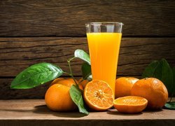 Pomarańcze położone obok szklanki z sokiem