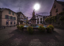 Posąg świętego Leona i fontanna na placu w Eguisheim o zmierzchu