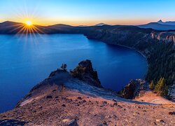Promienie zachodzącego słońca nad górskim jeziorem Crater Lake