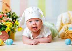 Radosne niemowlę w czapeczce pośród wielkanocnych dekoracji