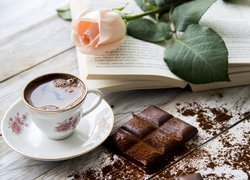Róża na książce obok kawy z czekoladą
