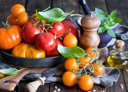 Różnorodne pomidory obok solniczki i oliwy