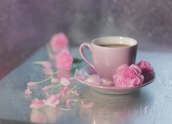 Różowa filiżanka kawy i goździki