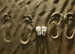 Ślady stóp i buciki dziecięce na piasku