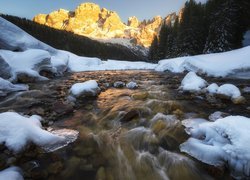 Śnieg na brzegach rzeki i rozświetlone słońcem Dolomity