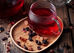 Suszone owoce na tacce obok herbaty w szklance