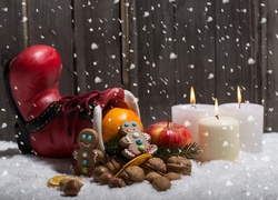Świąteczna kompozycja z butem pełnym smakołyków i świecami na śniegu