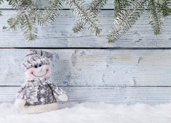 Świąteczny bałwanek na śniegu pod oszronionymi gałązkami