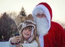 Szczęśliwa dziewczynka robi selfie z Mikołajem