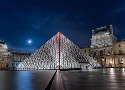 Szklana piramida na dziedzińcu Luwru we Francji nocą